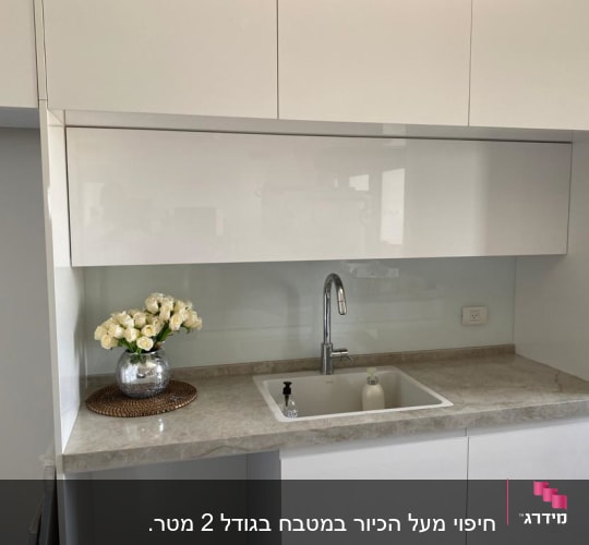 אגרטל זכוכית עם פרחים על השיש במטבח